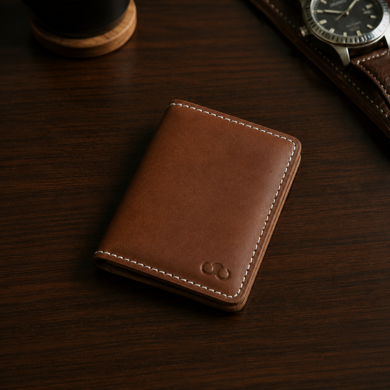 Handcrafted full-grain leather cardholder open on a dark walnut desk beside a mechanical watch